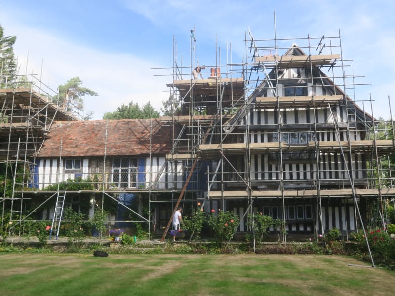 Substantial tudor property under construction surrounded with scaffolding.
